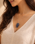 Woman wearing a necklace with a blue pendant against a neutral background