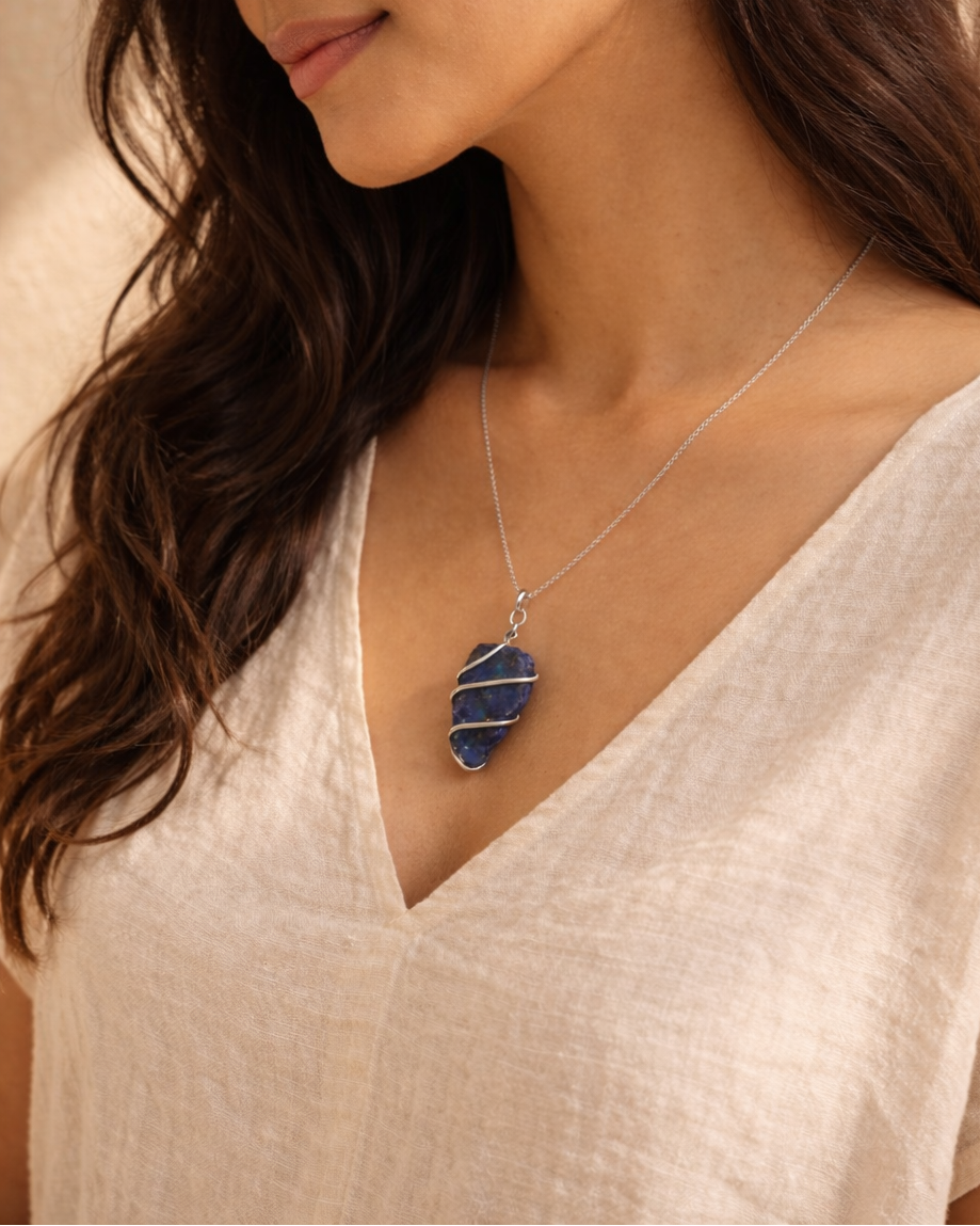 Woman wearing a necklace with a blue pendant against a neutral background