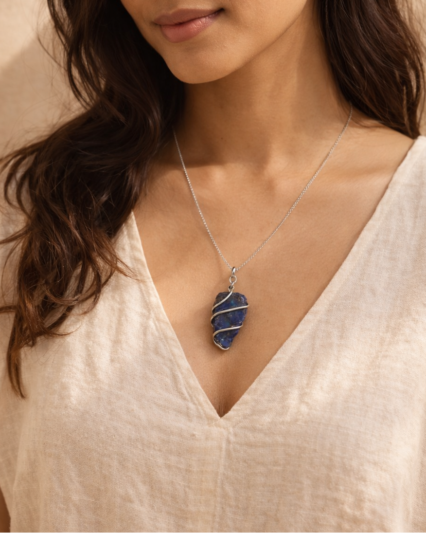 Woman wearing a necklace with a blue pendant against a beige background
