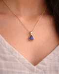 Gold necklace with a blue pendant worn by a person