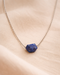 Necklace with a blue stone pendant on a beige fabric background