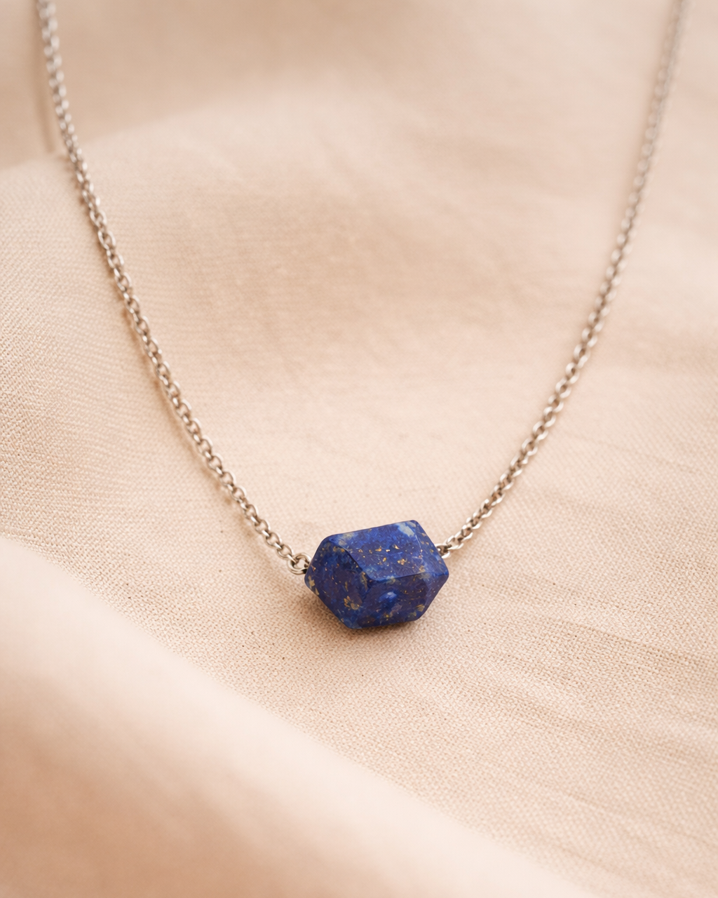 Necklace with a blue stone pendant on a beige fabric background
