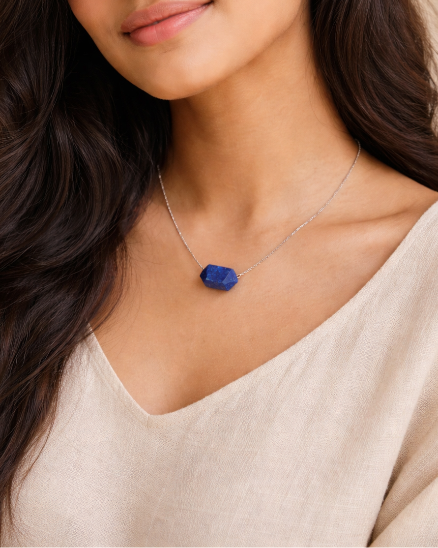 Woman wearing a necklace with a blue pendant against a neutral background