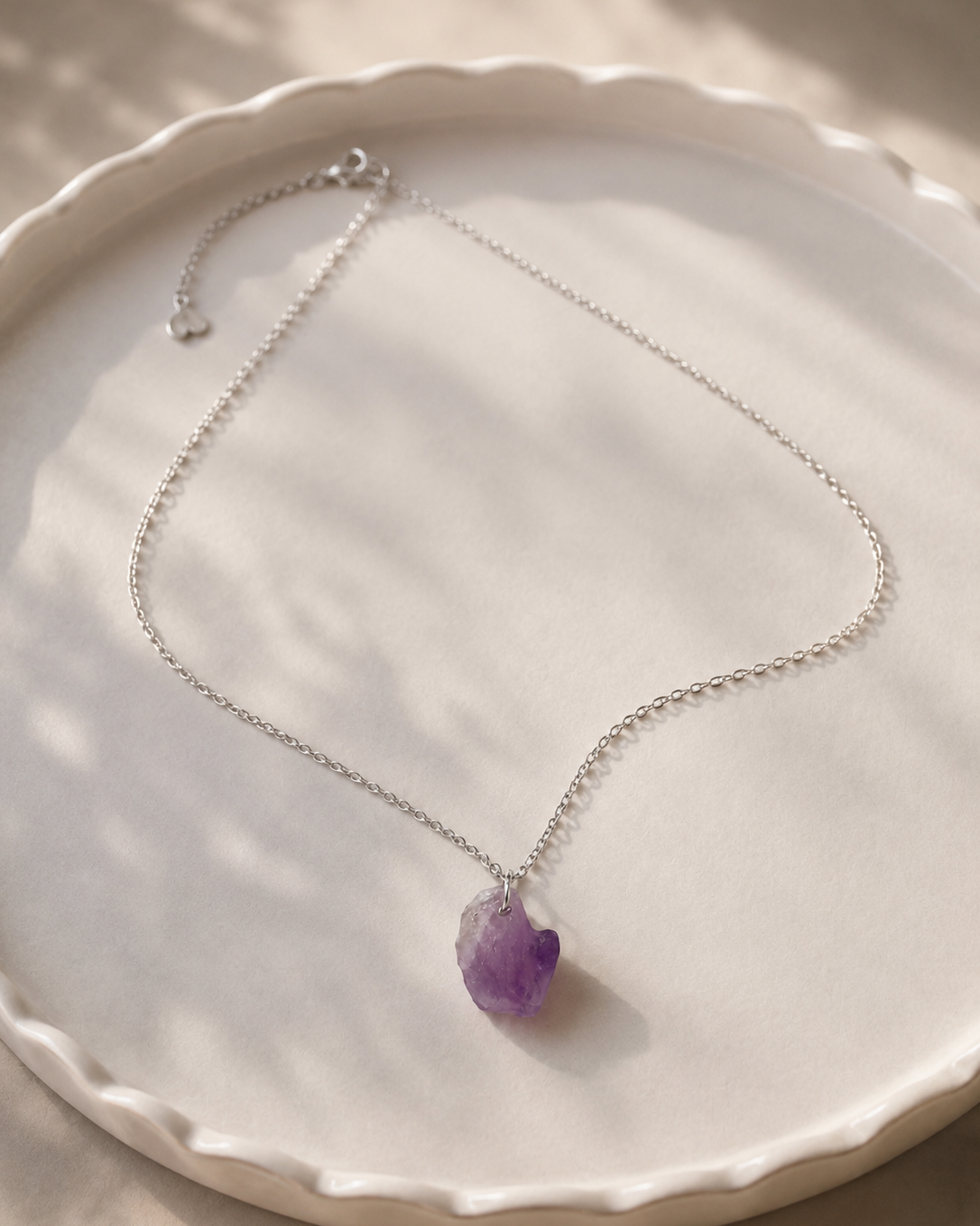 Necklace with a purple pendant on a white plate