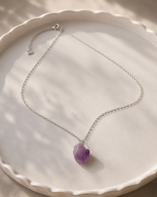 Necklace with a purple pendant on a white plate