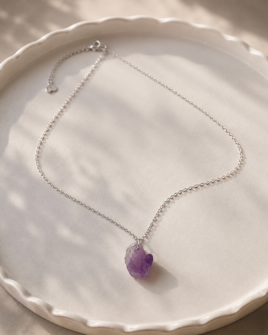 Necklace with a purple pendant on a white plate