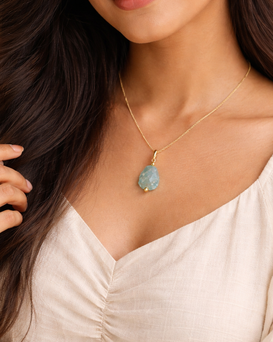 Woman wearing aquamarine pendant gold chain minimal style