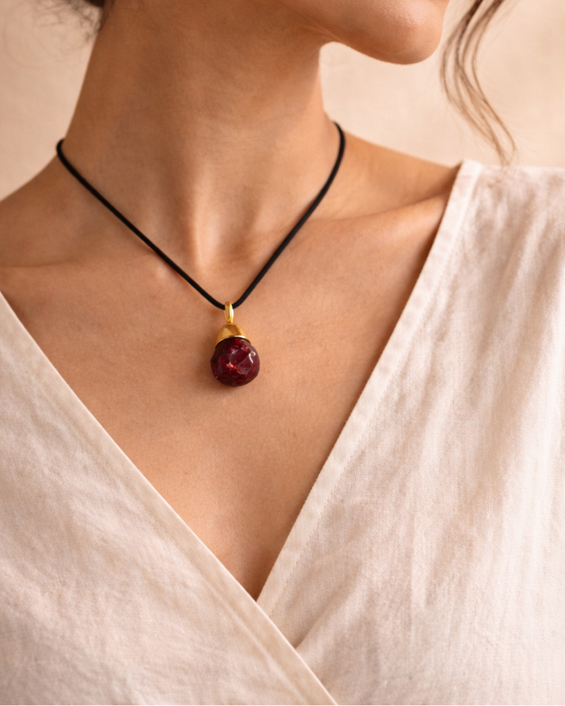 Woman wearing garnet pendant necklace with black cord