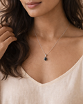 Woman wearing a delicate necklace against a neutral background