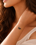 Woman wearing a delicate gold bracelet with a small crescent moon charm.