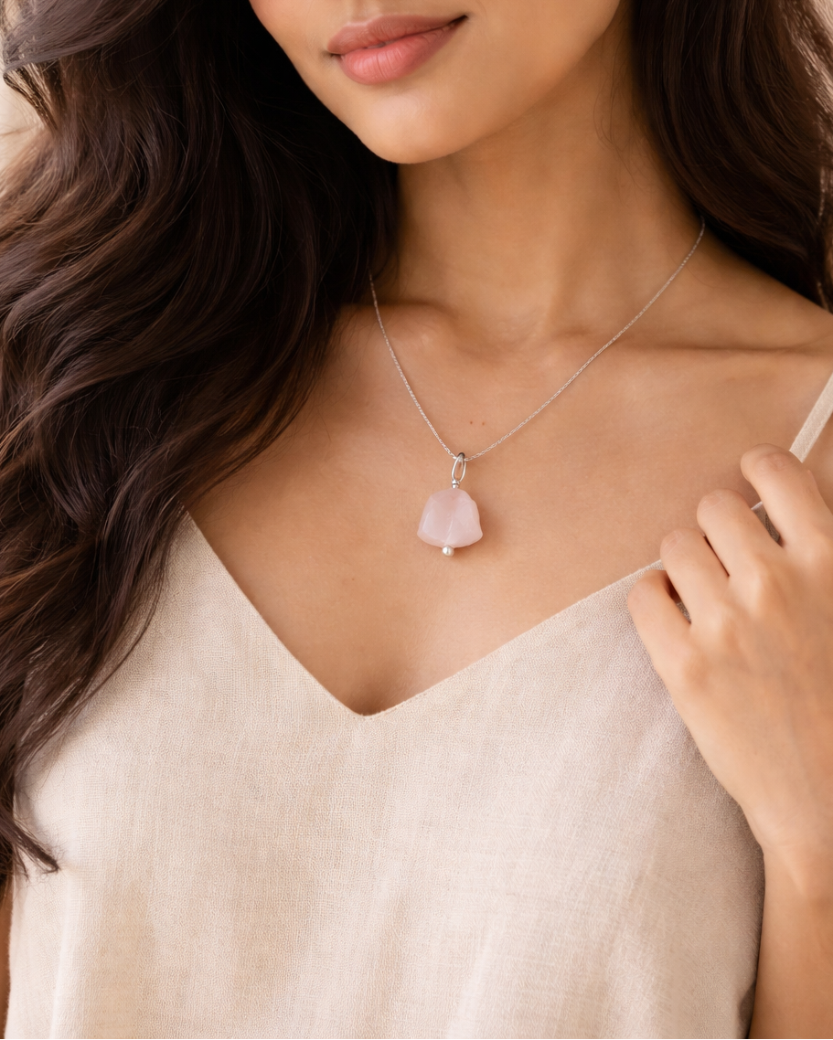 Woman wearing a necklace with a pink pendant against a neutral background