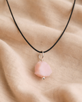 Necklace with a pink pendant on a beige fabric background