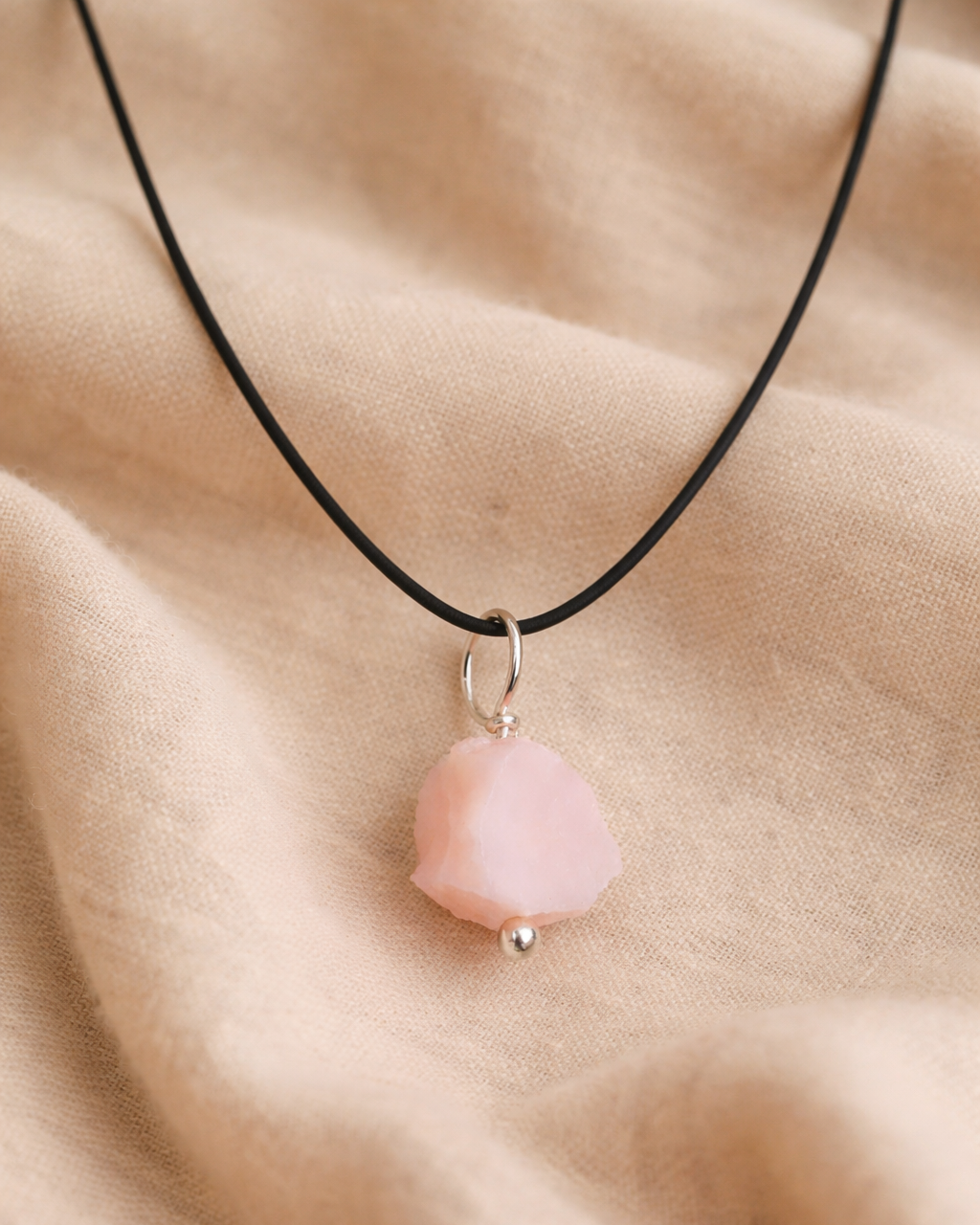 Necklace with a pink pendant on a beige fabric background