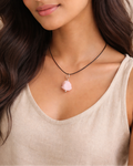 Woman wearing a necklace with a pink pendant against a neutral background