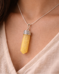 Yellow pendant necklace on a person wearing a beige top
