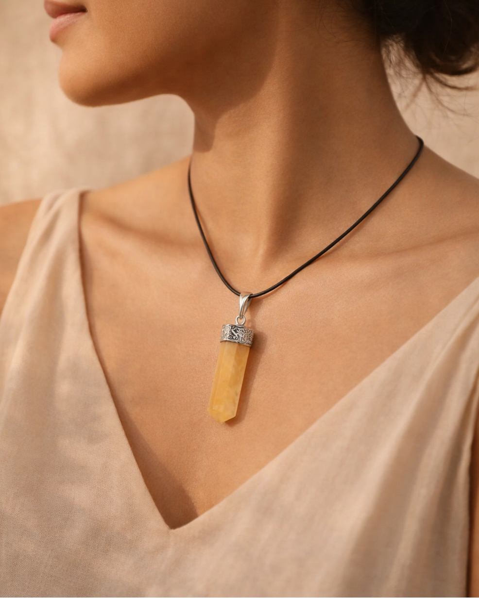 Woman wearing a necklace with a yellow pendant against a neutral background