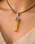 Necklace with a yellow pendant and silver clasp on a person's neck.
