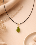 Necklace with a green pendant on a beige fabric background