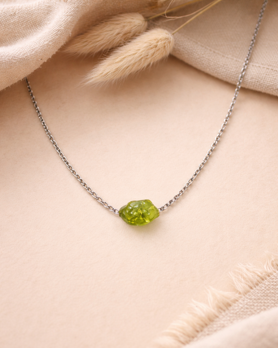 Necklace with a green gemstone on a beige fabric background