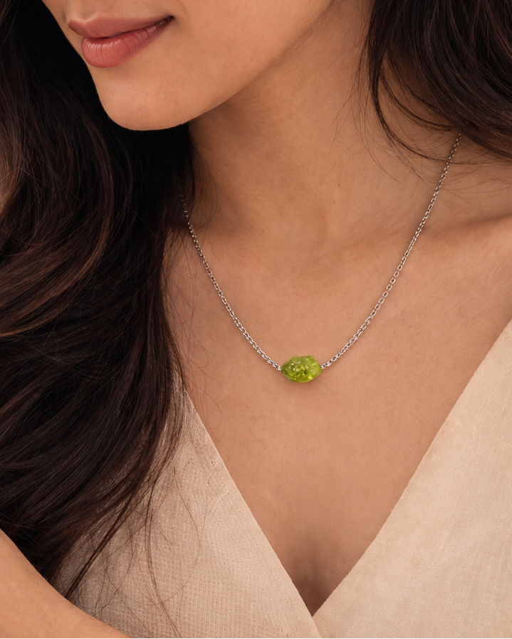Woman wearing a necklace with a green pendant outdoors