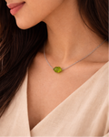 Woman wearing a necklace with a green gemstone