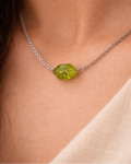 Necklace with a green gemstone on a person's neck
