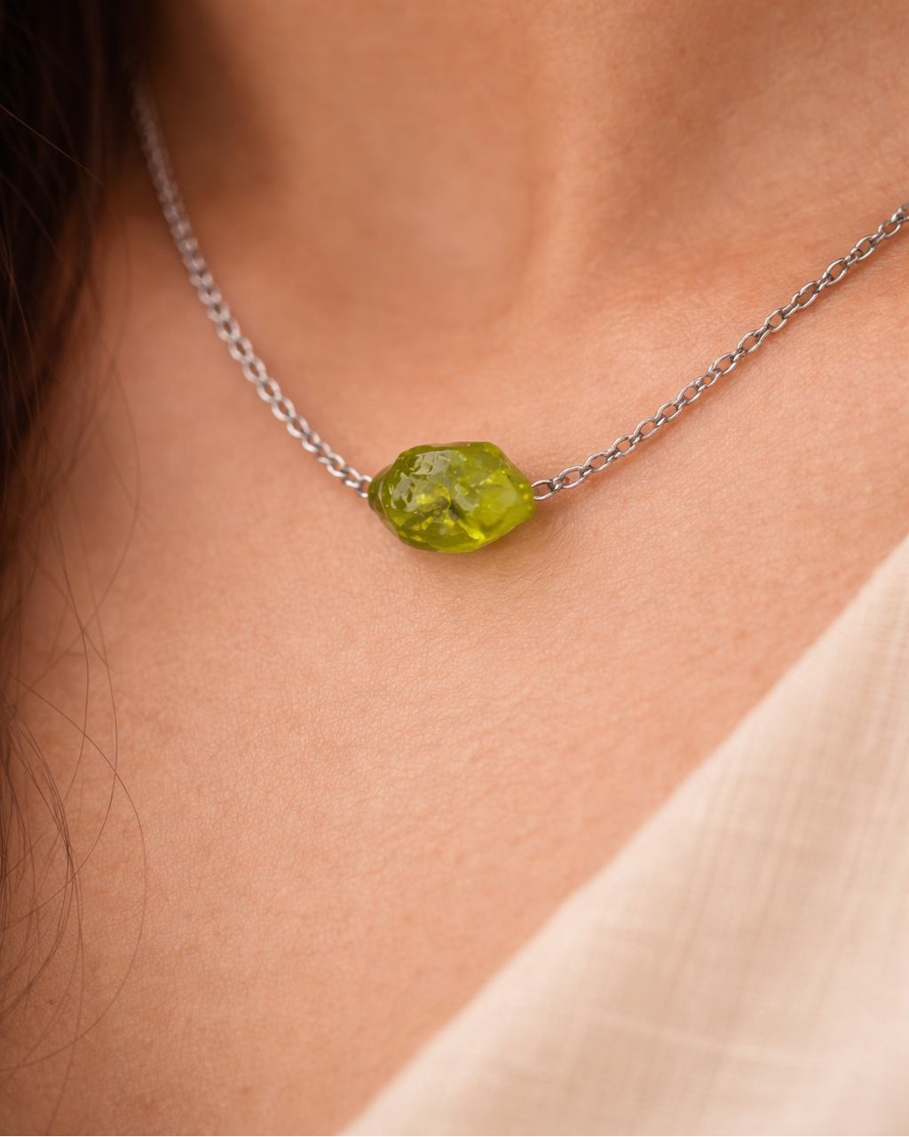 Necklace with a green gemstone on a person's neck