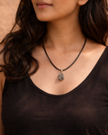 Woman wearing a black tank top and necklace against a brown background