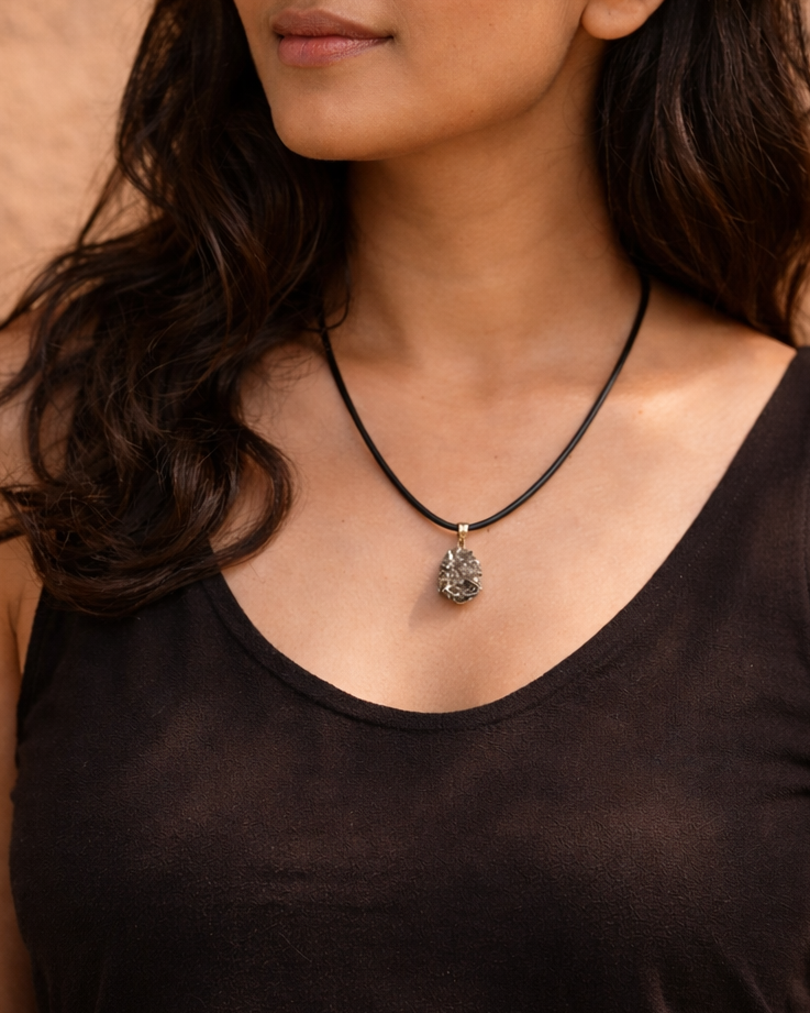 Woman wearing a black tank top and necklace against a brown background