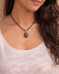 Woman wearing a necklace with a pendant against a beige background