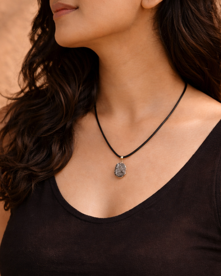 Woman wearing a black tank top and necklace against a brown background