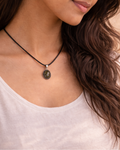 Woman wearing a necklace with a pendant against a neutral background