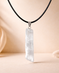 Crystal pendant necklace on a black cord against a beige background