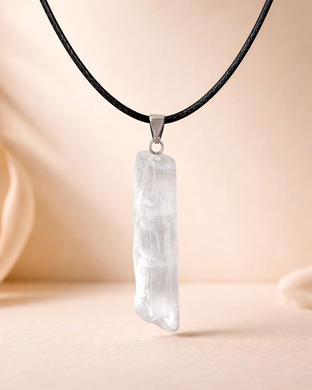 Crystal pendant necklace on a black cord against a beige background