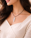 Woman wearing a necklace with a clear pendant against a neutral background