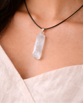 Necklace with a clear crystal pendant worn by a person