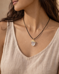 Woman wearing a necklace with a pendant against a neutral background