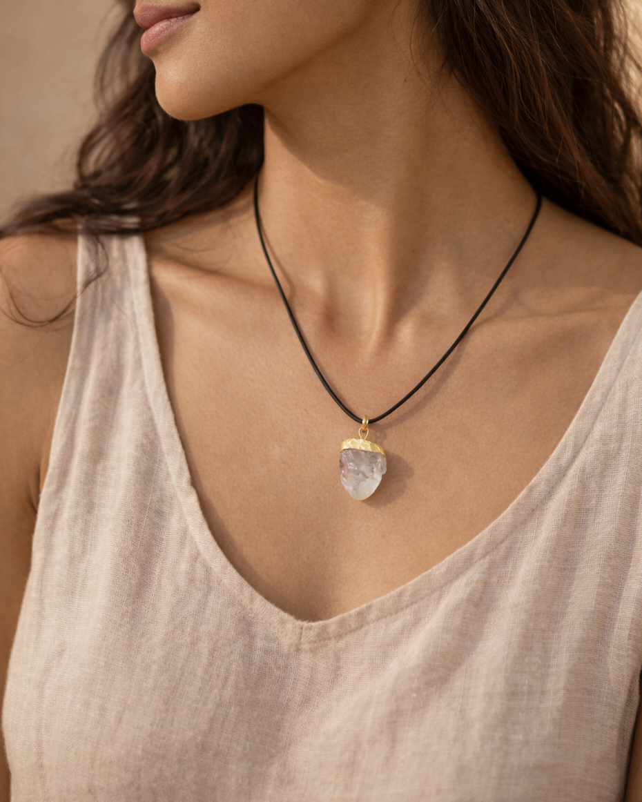 Woman wearing a necklace with a pendant against a neutral background