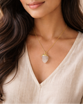 Woman wearing a gold necklace with a pendant against a neutral background