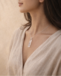 Woman wearing a necklace with a pendant against a beige background