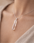Necklace with a clear crystal pendant worn by a person