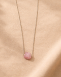 Necklace with a pink pendant on a beige fabric background