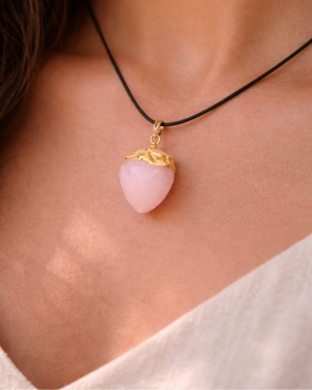 Necklace with a pink pendant and gold accent on a person's neck