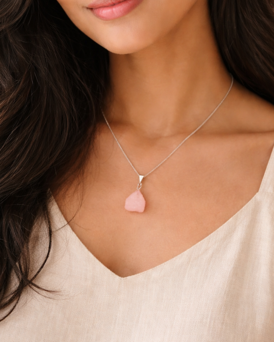 Woman wearing a necklace with a pink pendant against a neutral background