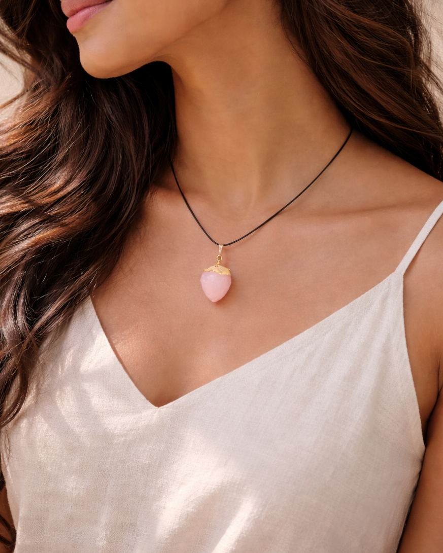 Woman wearing a necklace with a pink pendant against a neutral background