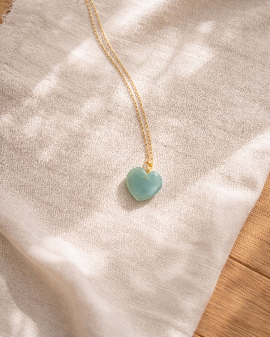 aquamarine heart pendant necklace on gold chain showing light blue natural stone texture