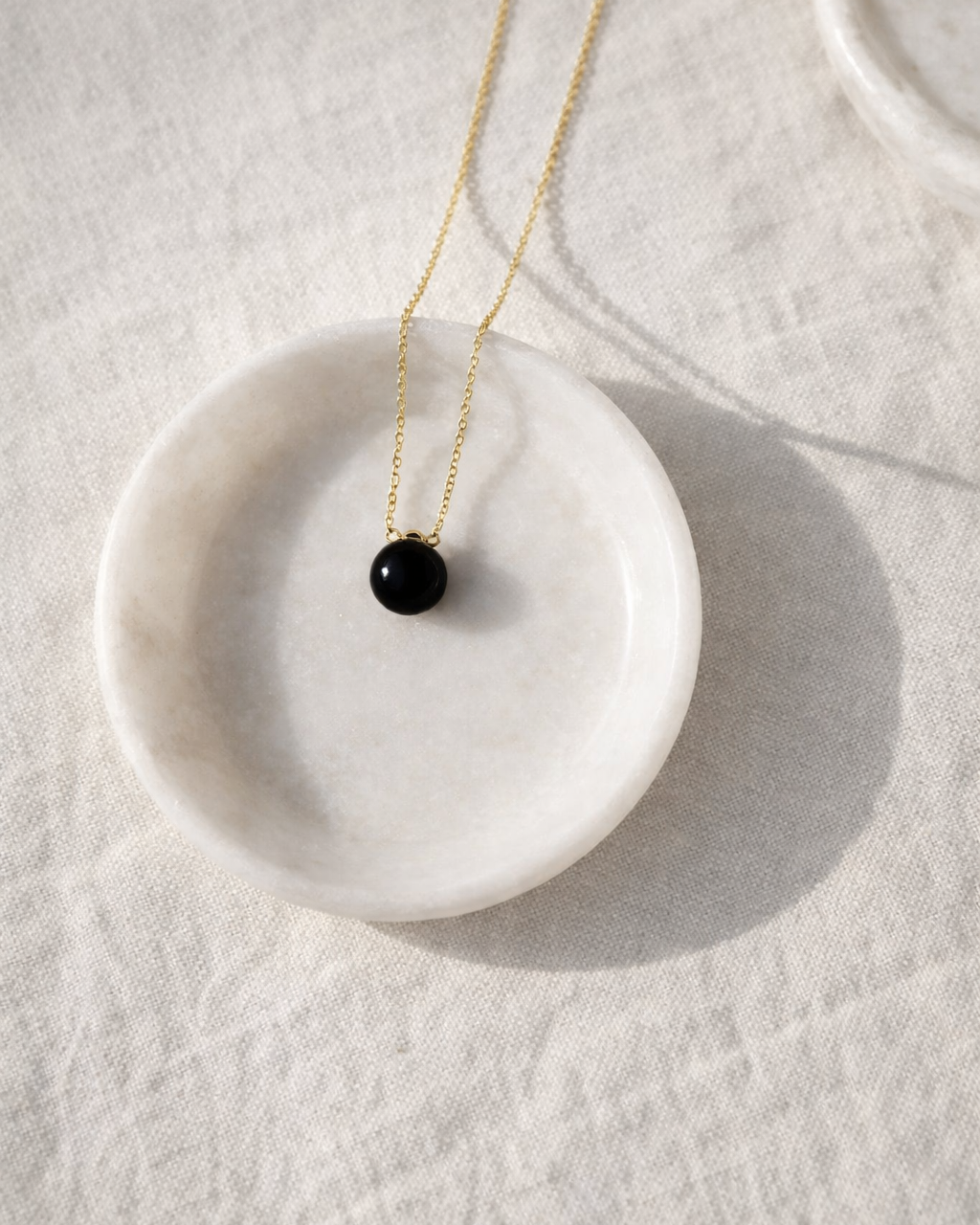 close up of black onyx heart drop pendant on gold chain showing smooth polished stone