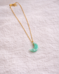 Malachite crescent moon pendant with gold chain displayed on neutral background, minimal aesthetic jewelry style