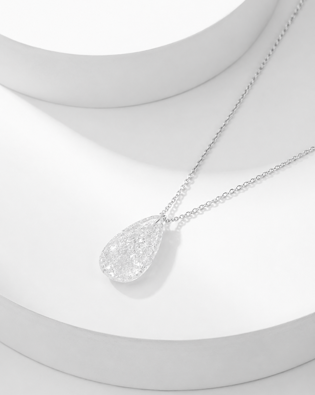 Natural clear quartz pavé teardrop pendant necklace on silver cable chain, white background