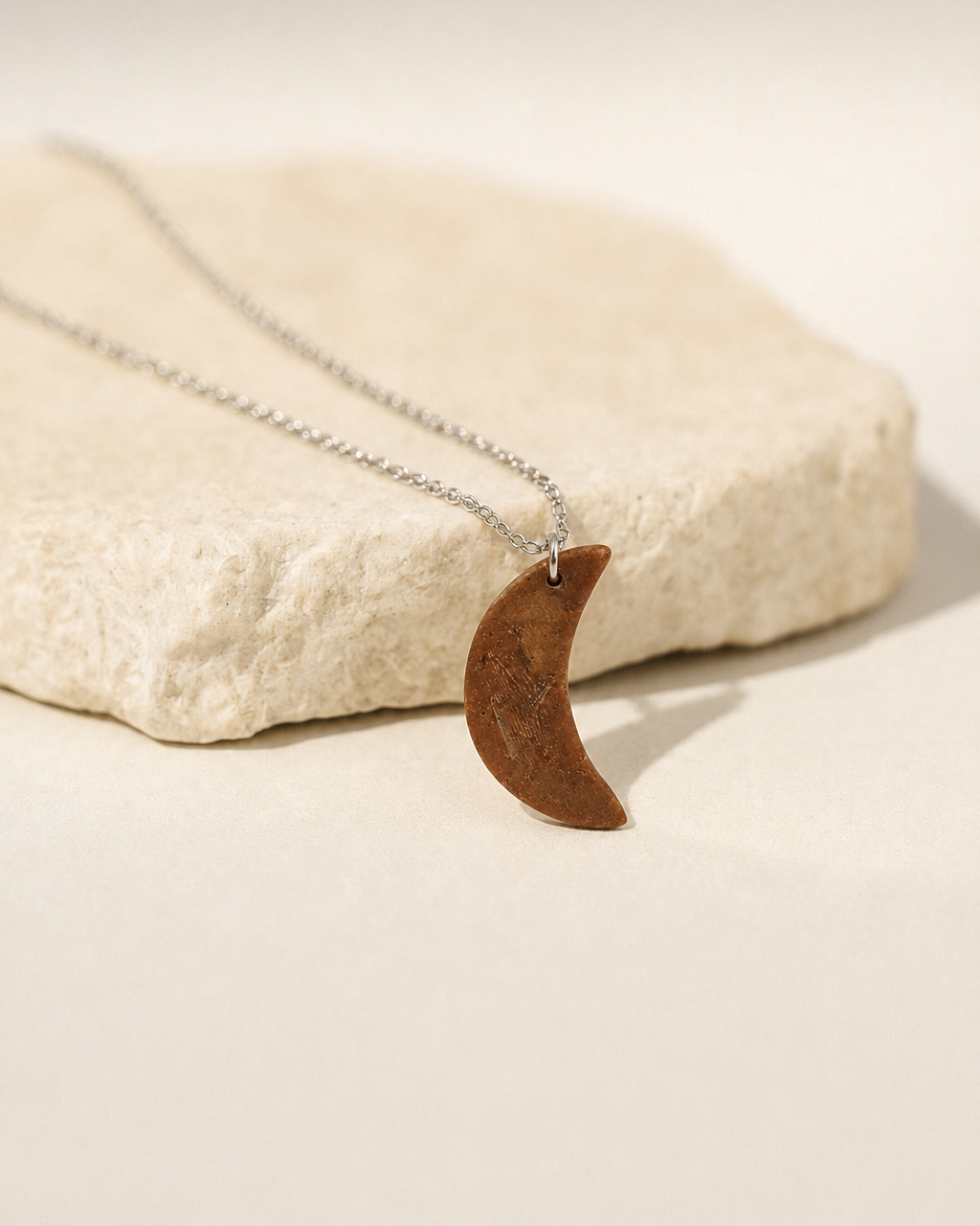 Natural Tiger Eye crescent moon pendant necklace displayed on stone surface